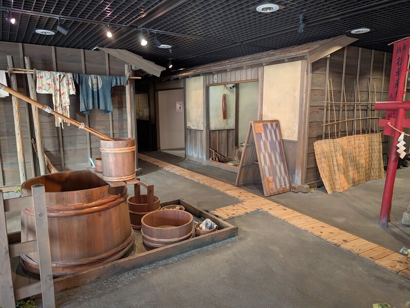 Recreation of an Edo-era square, showing the wooden well with buckets for washing, and the wooden slats over the surface drainage for dirty water.