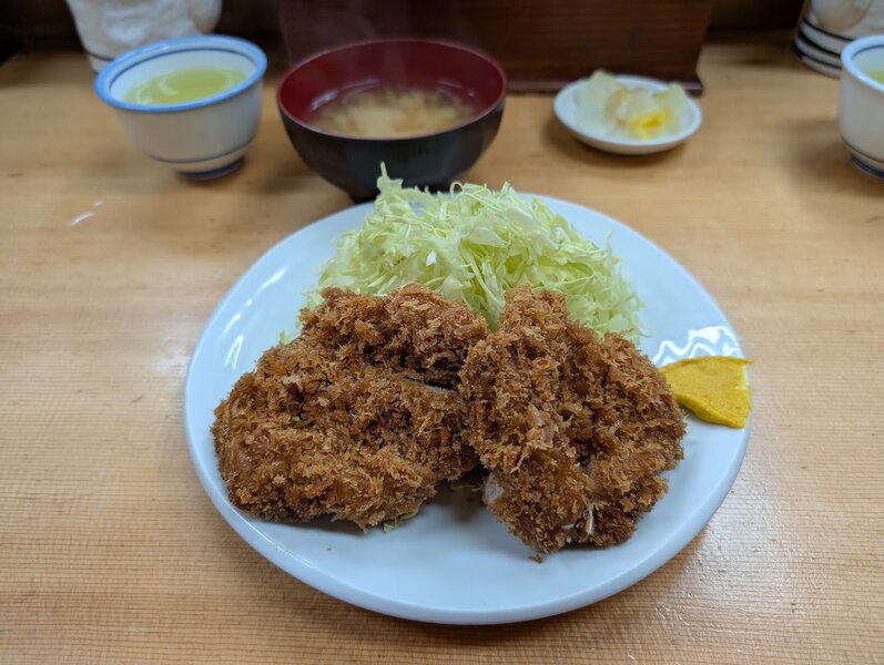 Close up of delicious tonkatsu with a stack of diced cabbage and some mustard on the side.