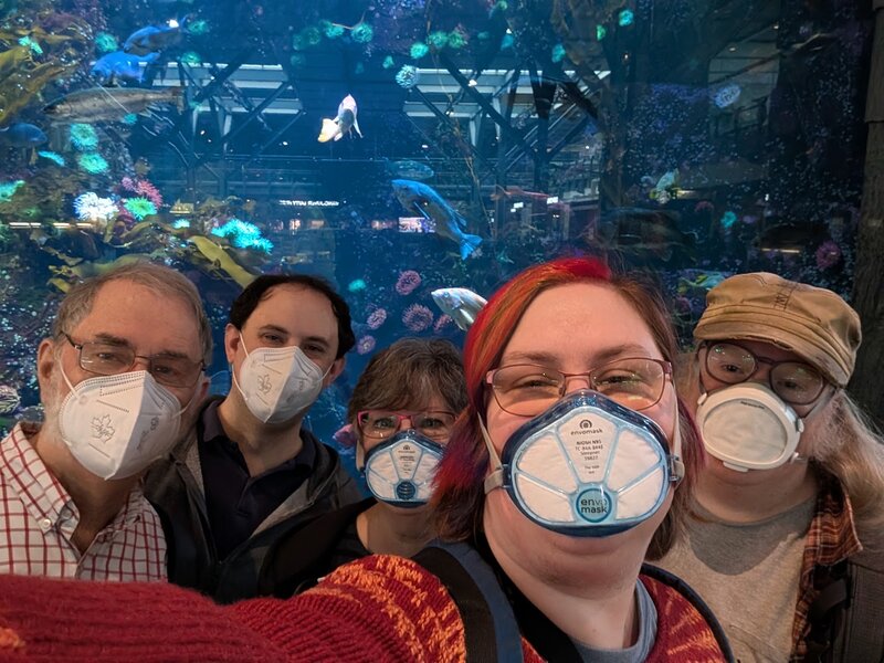 Selfie of Dad, Andrew, Mom, me and James in front of the aquarium at YVR. We're all masked.